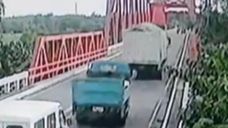As the white truck makes its way on to the bridge, a section collapses beneath the white and blue vehicles.