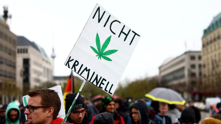 A man carries a sign reading "Not criminal" as he participates in a gathering with marijuana activists to mark the annual world cannabis day and to protest for legalization of marijuana, in front of the Brandenburg Gate, in Berlin, Germany, April 20, 2022
