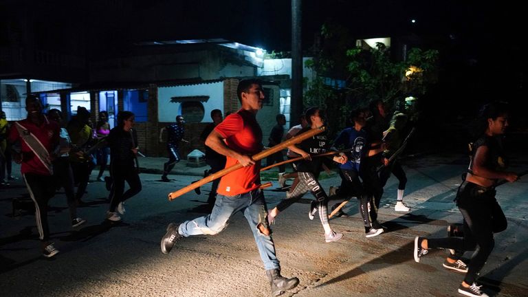 Orang-orang yang membawa tongkat berlari dan meneriakkan slogan-slogan pro-pemerintah setelah protes selama pemadaman listrik setelah Badai Ian di Havana, Kuba, 30 September 2022. REUTERS/Alexandre Meneghini