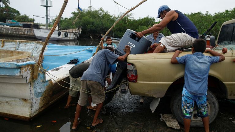 Fishermen load an outboard motor into a pickup truck as Hurricane Roslyn approaches tourist areas along Mexico's Pacific coast