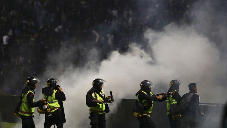 Police officers fire tear gas during a soccer match at Kanjuruhan Stadium in Malang, East Java, Indonesia, Saturday, Oct. 1, 2022. Clashes between supporters of two Indonesian soccer teams in East Java province killed over 100 fans and a number of police officers, mostly trampled to death, police said Sunday. (AP Photo/Yudha Prabowo)