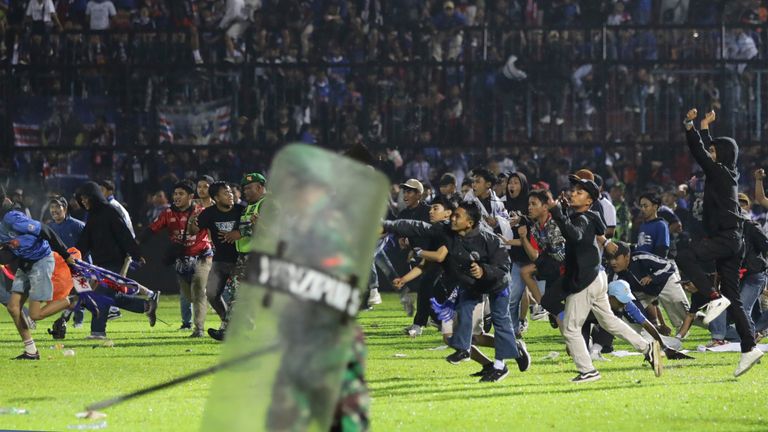 Soccer fans enter the pitch during a clash between supporters at Kanjuruhan Stadium in Malang, East Java, Indonesia, Saturday, Oct. 1, 2022. Clashes between supporters of two Indonesian soccer teams in East Java province killed over 100 fans and a number of police officers, mostly trampled to death, police said Sunday. (AP Photo/Yudha Prabowo)