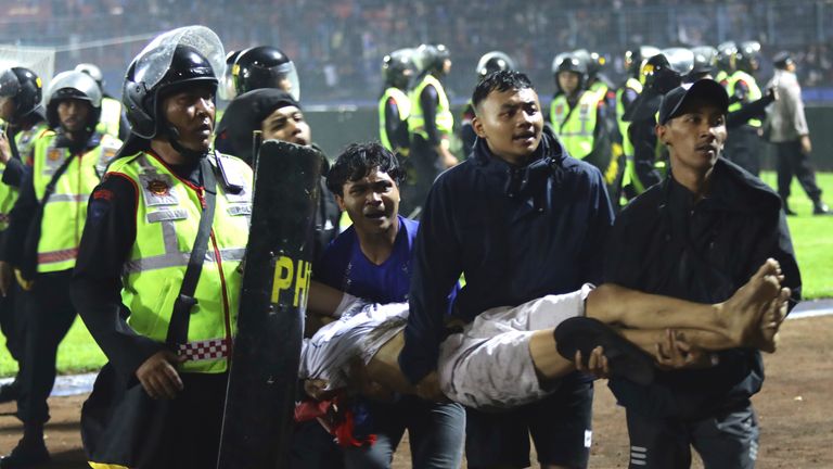 Fanii fotbalului poartă un bărbat rănit în urma ciocnirilor din timpul unui meci de fotbal pe stadionul Kanjuruhan din Malang, Java de Est, Indonezia, sâmbătă, 1 octombrie 2022. Panica în urma acțiunilor poliției a făcut peste 100 de morți, majoritatea călcați în picioare, a declarat duminică poliția.  (AP Photo/Yudha Prabowo)