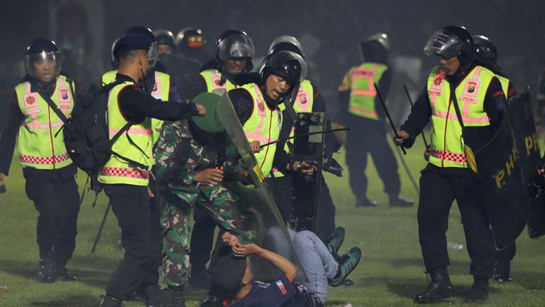Security officers detain a fan during a clash between supporters of two Indonesian soccer teams at Kanjuruhan Stadium in Malang, East Java, Indonesia, Saturday, Oct. 1, 2022. Clashes between supporters of two Indonesian soccer teams in East Java province killed over 100 fans and a number of police officers, mostly trampled to death, police said Sunday. (AP Photo/Yudha Prabowo)