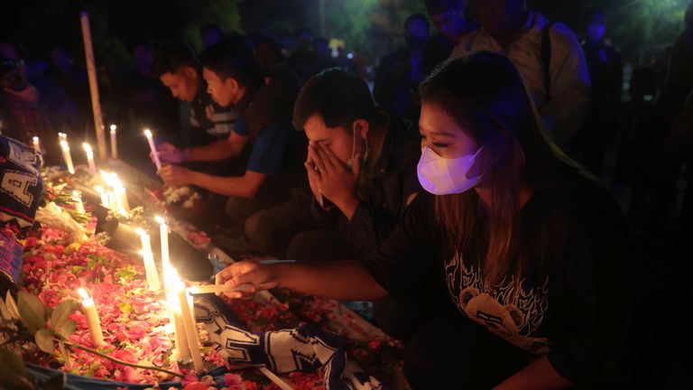 People pray and light candles during a vigil for the victims of Saturday&#39;s soccer match stampede outside Kanjuruhan Stadium where it broke out, in Malang, East Java, Indonesia, Sunday, Oct. 2, 2022. Panic at an Indonesian soccer match Saturday left over 100 people dead, most of whom were trampled to death after police fired tear gas to stop the rioters. (AP Photo/Trisnadi)