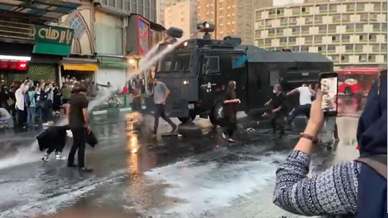 A young women films during a protest in Iran earlier in October 