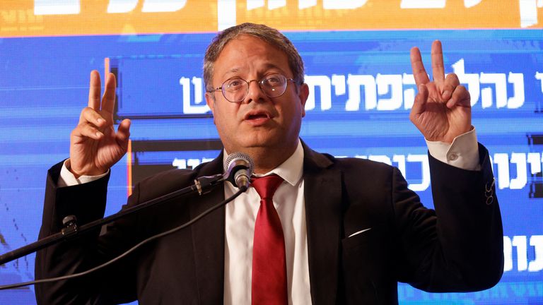 Israeli far-right politician Itamar Ben-Gvir holds up both hands in the &#39;V for victory&#39; gesture from behind a podium at a news conference