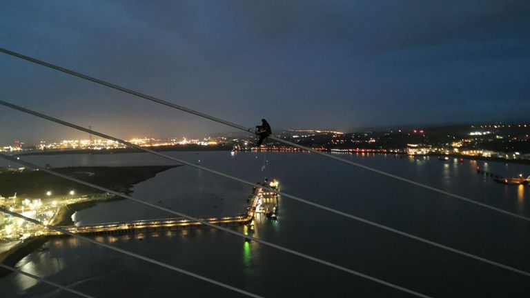 Handout photo issued by Just Stop Oil of one of their activists scaling the Queen Elizabeth II Bridge at the Dartford Crossing on Monday. Police have closed the major road bridge linking Essex and Kent after a report that two people have "climbed onto the bridge and are currently at height". Issue date: Monday October 17, 2022.
