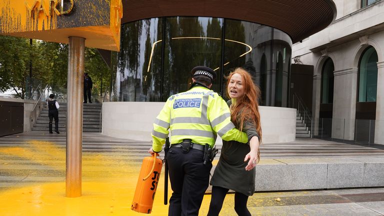 Police officers detain a Just Stop Oil protester after she spray painted a sign outside New Scotland Yard in London. Picture date: Friday October 14, 2022.