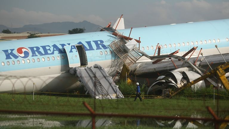 A man walks beside a damaged Korean Air plane after it overshot the runway at the Mactan-Cebu International Airport in Cebu, central Philippines early Monday Oct. 24, 2022. The Korean Air plane overshot the runway while landing in bad weather in the central Philippines late Sunday, but authorities said all 173 people on board were safe. (AP Photo/Juan Carlo De Vela)