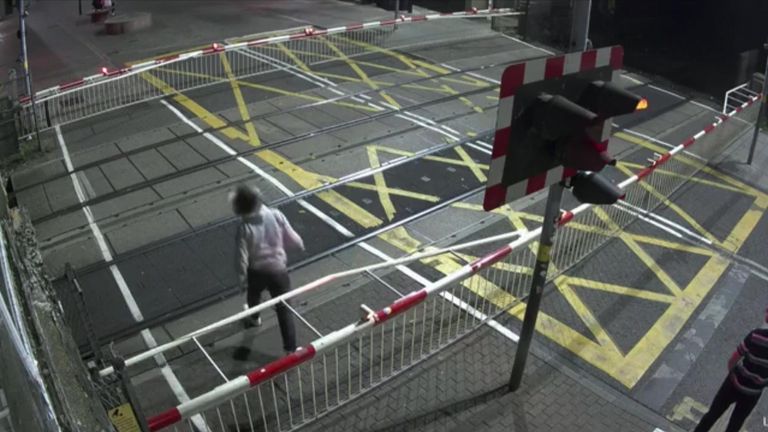 Man climbs over barriers at level crossing and is almost hit by freight train