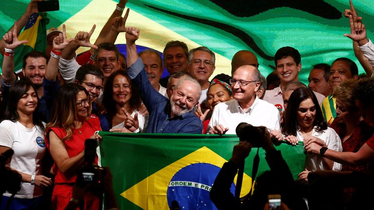 Lula greets the crowd with his wife (red)