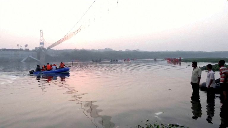 People look on as rescuers in boats work at the site of a suspension bridge collapse in Morbi town in the western state of Gujarat, India, October 31, 2022.    ANI via REUTERS    THIS IMAGE HAS BEEN SUPPLIED BY A THIRD PARTY INDIA OUT. NO COMMERCIAL OR EDITORIAL SALES IN INDIA