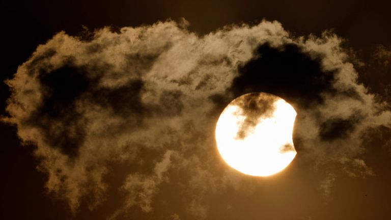 A partial solar eclipse is pictured behind the cloud during the sunset in Kathmandu, Nepal