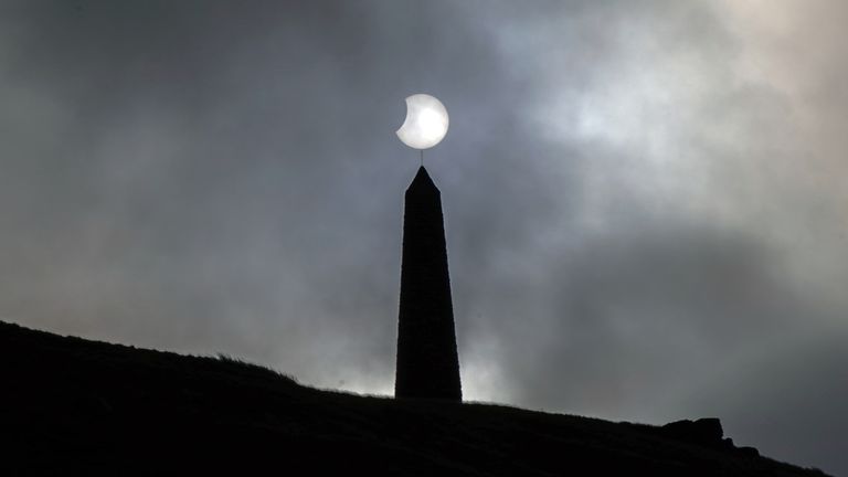 The sun breaks through the clouds during a partial solar eclipse visible from a 1,300-foot-tall Stoodley Pike mountain in the South Pennines, West Yorkshire. Image Date: Tuesday, October 25, 2022.