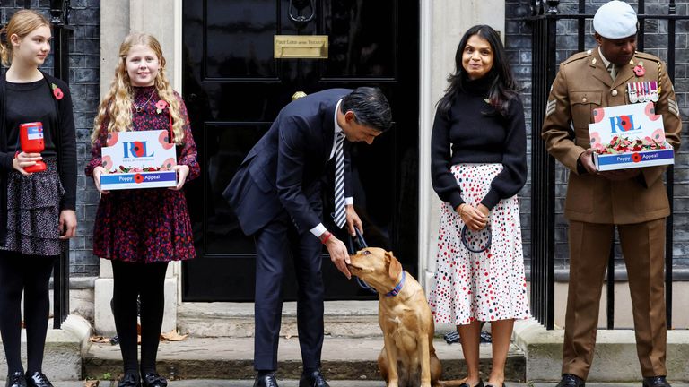 British Prime Minister Rishi Sunak pets his dog Nova, next to his wife Akshata Murty, as they meet volunteers from the Royal British Legion outside Number 10 Downing Street in London, Britain, October 31, 2022. REUTERS/Henry Nicholls.