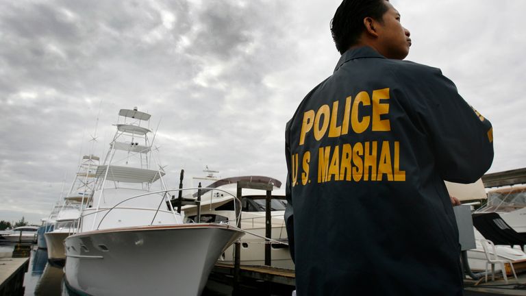 Roland Ubaldo of the U.S. Marshal&#39;s office keeps watch near a vintage Rybovich M/V "The Bull" sportfish yacht (L), owned by Bernard Madoff, in the dockyard at the National Liquidators in Davie, Florida November 16, 2009. The 55-footer is among three Madoff vessels up for sale in a live auction tomorrow with proceeds going to victim restitution. REUTERS/Hans Deryk (UNITED STATES CRIME LAW BUSINESS SOCIETY SPORT YACHTING)