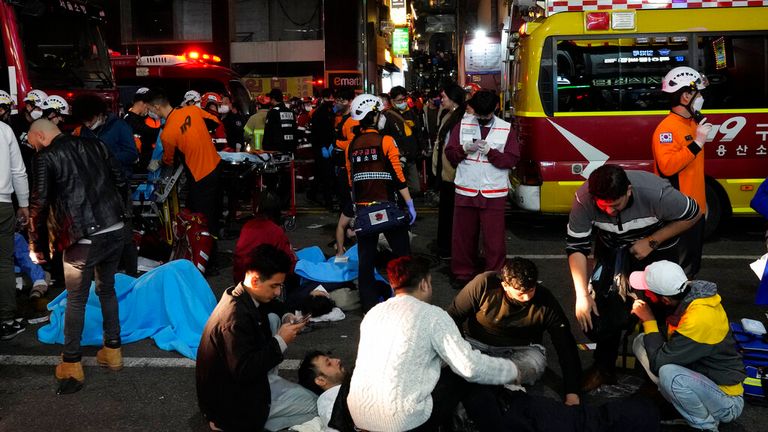 Rescue workers and firefighters try to help injured people near the scene of a crowd surge in Seoul, South Korea