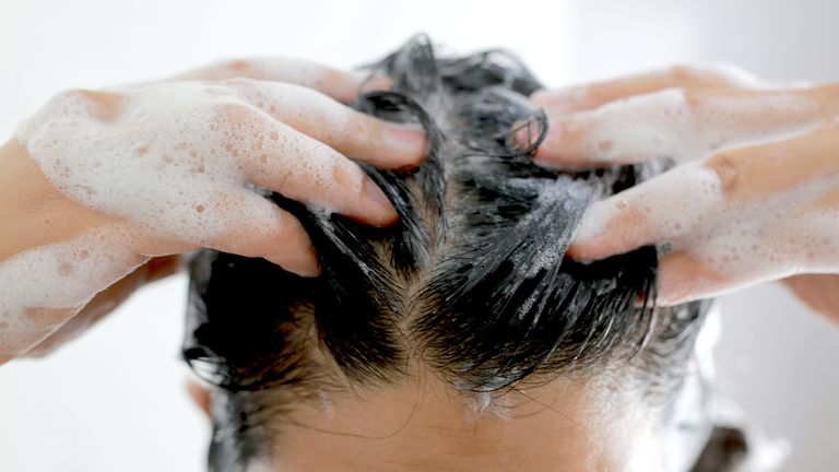 Woman is washing her hair with shampoo
