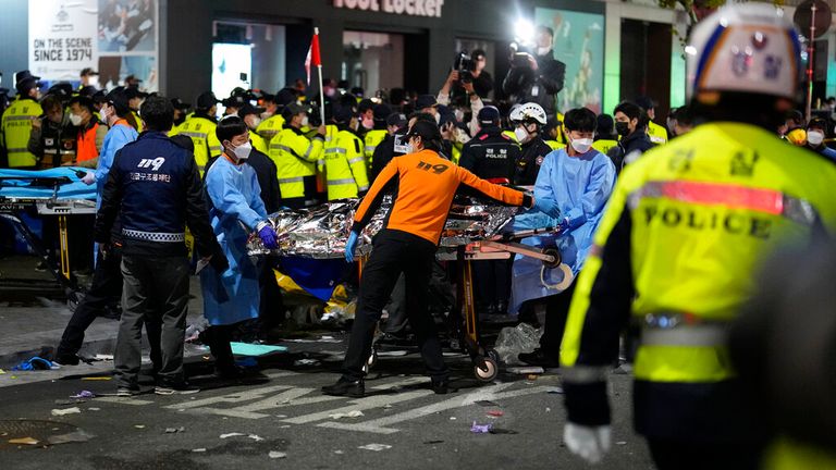 Rescue workers carry a victim on the street near the scene in Seoul, South Korea, Sunday, Oct. 30, 2022. Scores of people were killed and others were injured as they were crushed by a large crowd pushing forward on a narrow street during Halloween festivities in the capital, South Korean officials said. (AP Photo/Lee Jin-man)