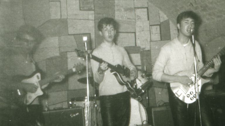Lennon on microphone, playing at Liverpool&#39;s Cavern Club with the Beatles in 1961
