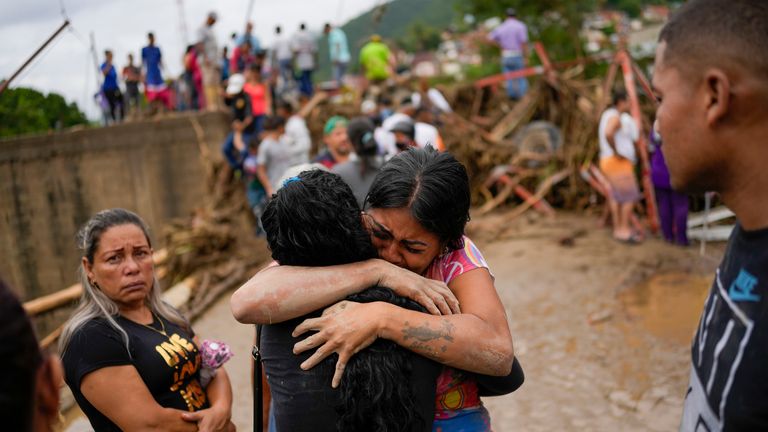Residents embrace in Las Tejerias, Venezuela, Sunday, Oct. 9, 2022, after intense rain caused a river to overflow flooding the town. (AP Photo/Matias Delacroix)