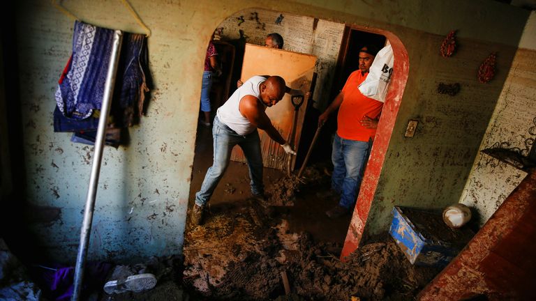 Residents remove mud from inside a house that was hit by devastating floods following heavy rain, in Las Tejerias, Aragua state, Venezuela