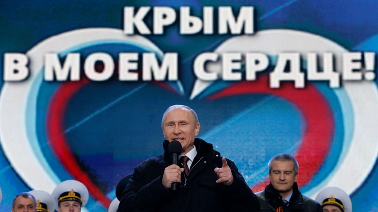 Vladimir Putin, bir miting ve bir konser sırasında izleyicilere hitap ediyor. "Biz beraberiz" Ukrayna'nın Kırım'ın Rusya'ya ilhakını desteklemek için Kırım Başbakanı Sergei Aksyonov ve parlamento başkanı Vladimir Konstantinov (solda) arka planda görülüyor, Moskova'nın merkezindeki Kızıl Meydan'da, 18 Mart 2014.
