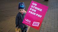 A child holds a placard, as lecturers on the picket line outside the University of Birmingham in a dispute over pay, working conditions and pensions. Picture date: Thursday November 24, 2022.