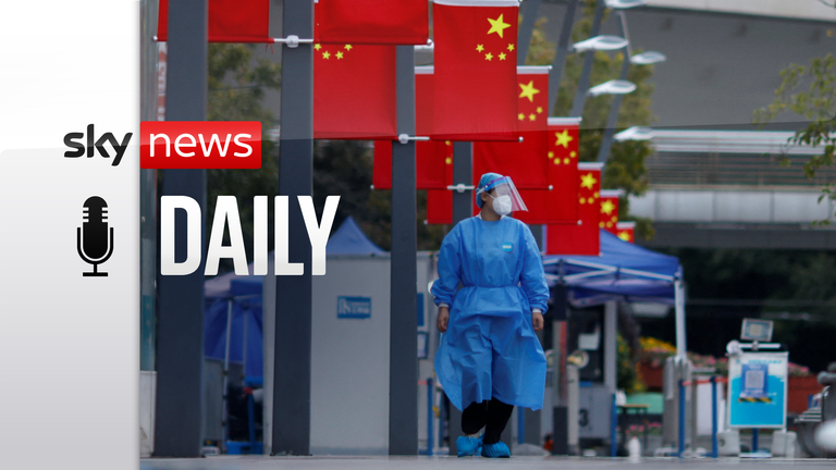 A medical worker in a protective suit walks under Chinese national flags, following the coronavirus disease (COVID-19) outbreak in Shanghai, China, October 21, 2022. REUTERS/Aly Song