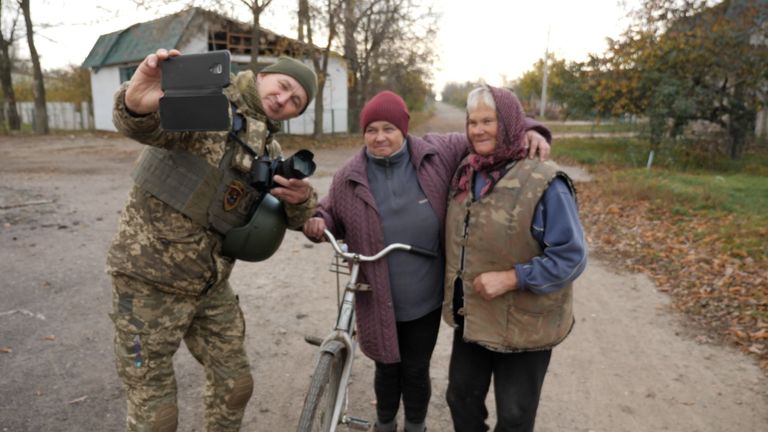 Bir asker, dokuz ay süren korkunç işgalin bitişini anmak için sivillerle selfie çekiyor. 