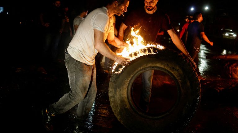 Supporters of Brazil's President Jair Bolsonaro move a tire, as they block highway BR-060 during a protest against President-elect Luiz Inacio Lula da Silva, who won a third term following the presidential election run-off, near Abadiania, Brazil, October 31, 2022. REUTERS/Ueslei Marcelino
