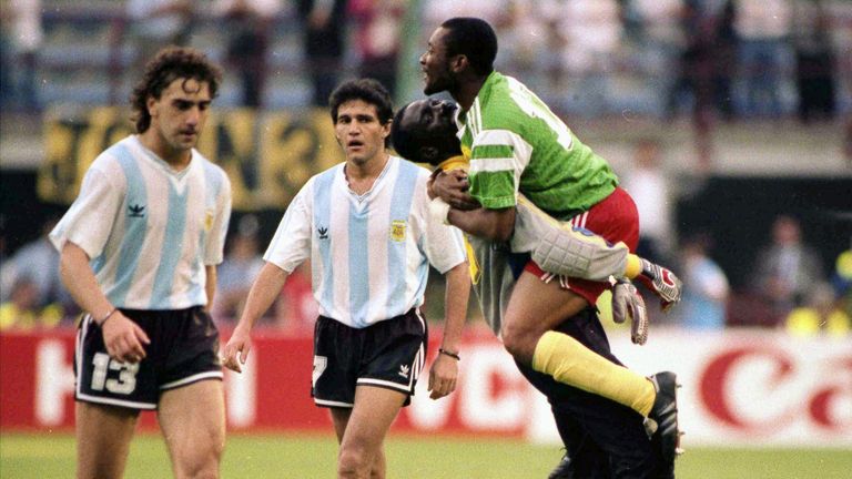 FILE - In this June 8, 1990 file photo, dejected Argentine players Nestor Gabriel Lorenzo, left, and Jorge Luis Burruchaga walk off the pitch, past unidentified celebrating Cameroon players, after the opening match of the soccer World Cup, in Milan, Italy. On this day: Opening day in World Cup history has produced its fair share of shocks, not least when Cameroon defeated defending champion Argentina in 1990. (AP Photo/File)