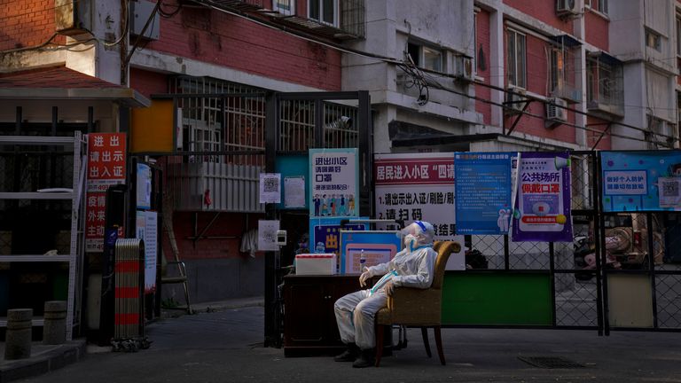 A security guard in protective gear monitors an entrance gate to a neighborhood in Beijing.  Photo: AP