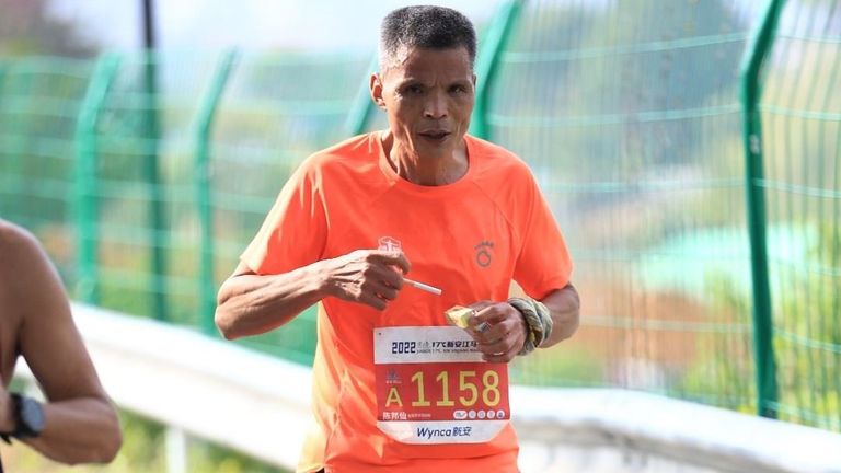 The eccentric runner is pictured pulling a cigarette out of a box as he ran the race