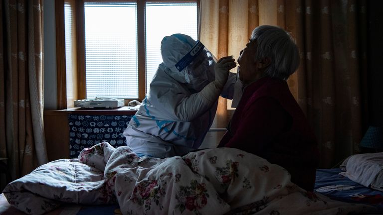A medical worker in protective suit collects a swab from a bedridden elderly at a house during the second round of citywide nucleic acid testing following the recent coronavirus disease (COVID-19) outbreak in Shijiazhuang, Hebei province, China January 13, 2021. cnsphoto via REUTERS ATTENTION EDITORS - THIS IMAGE WAS PROVIDED BY A THIRD PARTY. CHINA OUT.