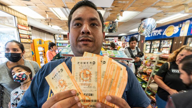 Hector Solis holds up lottery tickets purchased with his co-workers for the Saturday drawing