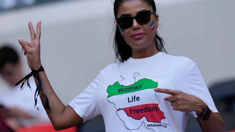 A fan wears a black ribbon and a t-shirt reading &#39;Woman, Life, Freedom&#39; in memory of Mahsa Amini at the match