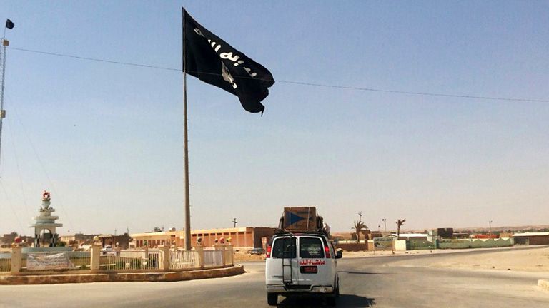 FILE - This Tuesday, July 22, 2014 file photo shows a motorist passing by a flag of the Islamic State group in central Rawah, 175 miles (281 kilometers) northwest of Baghdad, Iraq. Iraq’s Defense Ministry said Friday, Nov. 17, 2017 Iraqi forces have retaken the last IS-held town in the country, more than three years after the militant group stormed nearly a third of Iraqi territory.(AP Photo, File)