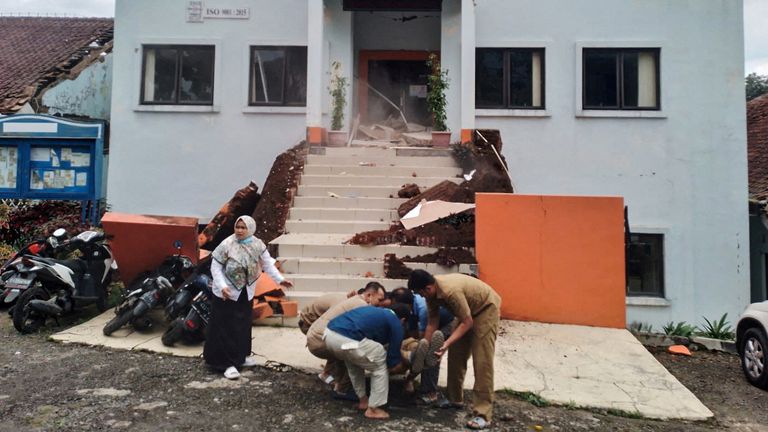 Municipality officers evacuate their injured colleague. Pic: BPBD/Reuters