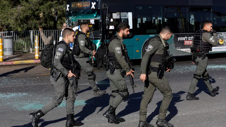 Israeli border police walk past a damaged bus following an explosion at a bus stop in Jerusalem  