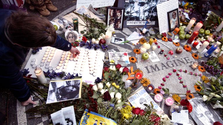 A woman lights candles that spell out John on a mosaic circle with the word Imagine on it to honor deceased John Lennon in Central Park&#39;s Strawberry Fields in New York December 8, 2005. Former Beatles member Lennon was shot and killed by Mark David Chapman in front of his apartment twenty five years ago. REUTERS/Keith Bedford