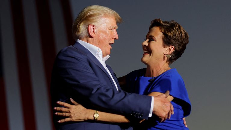 Former U.S. President Donald Trump embraces Republican candidate for Governor of Arizona Kari Lake on stage during a rally ahead of the midterm elections, in Mesa, Arizona, U.S., October 9, 2022. REUTERS/Brian Snyder