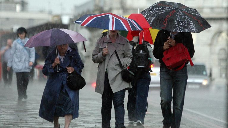 People walk through wind and rain in London, as a summer storm passes over the capital.