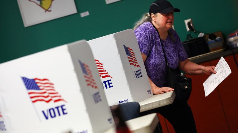 Bir seçmen, Harrisburg, Pennsylvania şehir merkezindeki 2022 ABD ara seçimleri sırasında oy pusulasını bir sandık merkezinde taşıyor