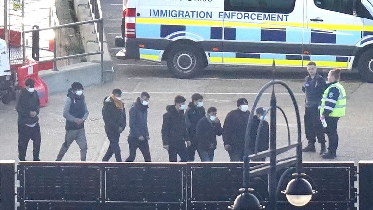 A group of people thought to be migrants walk through the Border Force compound in Dover, Kent