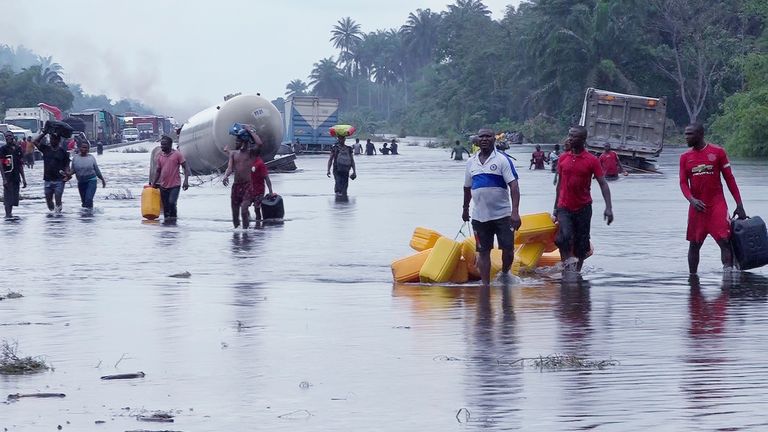 Nijerya'nın Bayelsa kentinde 20 Ekim 2022'de insanlar su basmış yollarda yürüyor. 