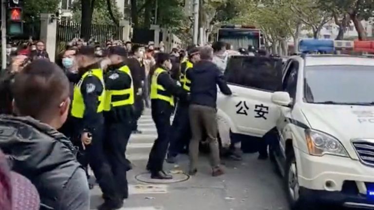 Police officers detain a man into a police van after his address to the crowd at the place where candlelight vigil was held for the victims of the Urumqi fire, in Shanghai