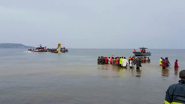 Rescuers in boats and standing in the water are seen around the tail fin of a crashed Precision Air passenger aircraft on the shores of Lake Victoria in Bukoba, in western Tanzania Sunday, Nov. 6, 2022. The small passenger plane crashed Sunday morning into Lake Victoria near Bukoba airport and the company Precision Air said the flight was coming from the coastal city of Dar es Salaam, though it was not immediately clear how many people were on board. (AYO TV via AP)