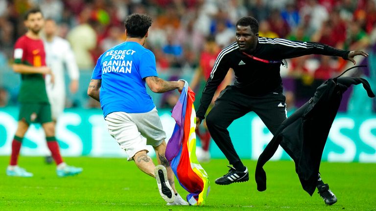 A pitch invader runs across the field with a rainbow flag during the World Cup group H soccer match between Portugal and Uruguay, at the Lusail Stadium in Lusail, Qatar, Monday, Nov. 28, 2022. (AP Photo/Petr David Josek)